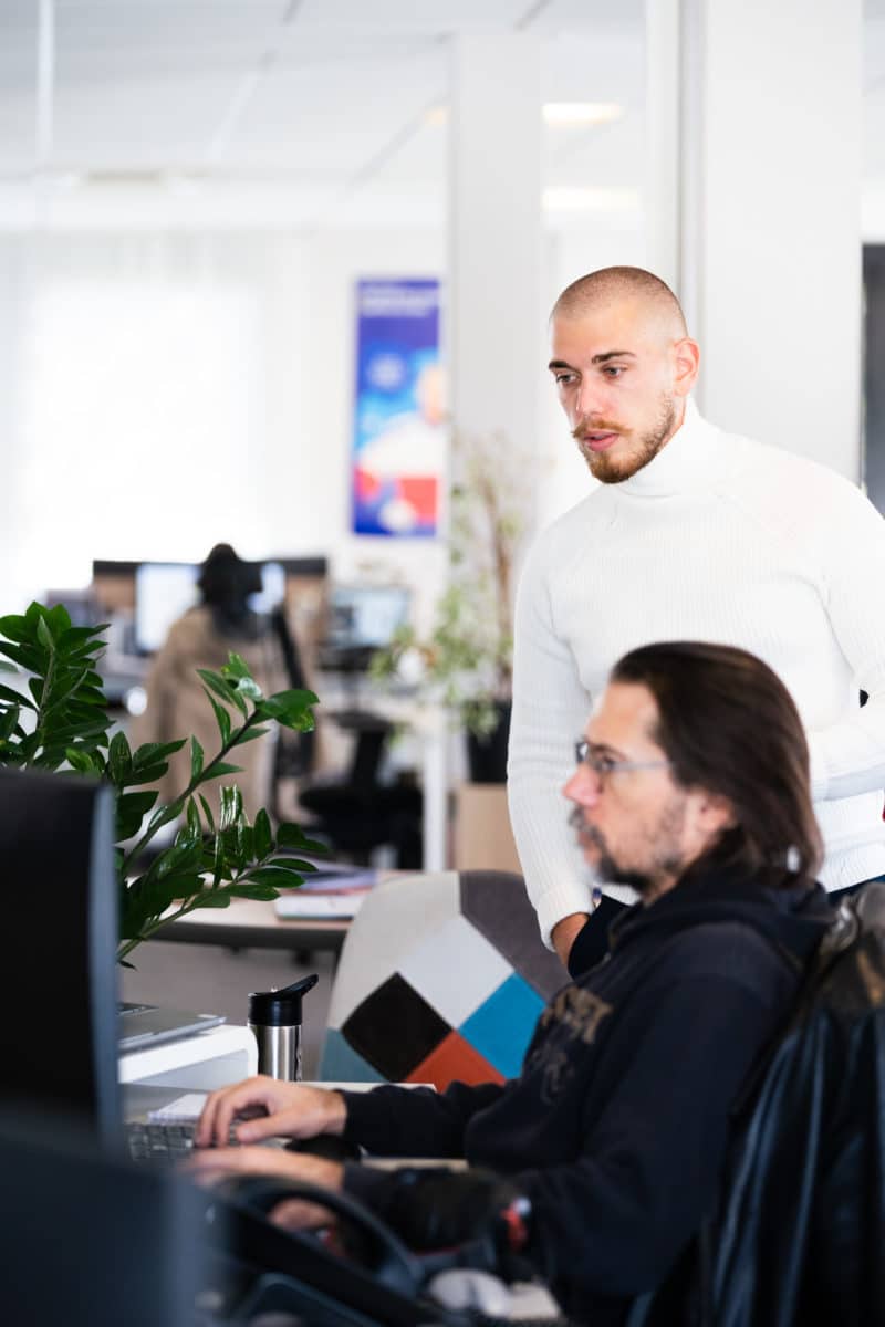 Deux hommes dans un bureau, l'un assis, l'autre debout